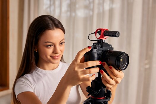 Frau stellt Kamera mit VIDEOMICRO II von RØDE auf einem Stativ ein.