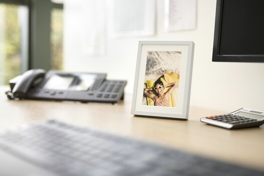 Foto in einem hellen Bilderrahmen auf dem Schreibtisch