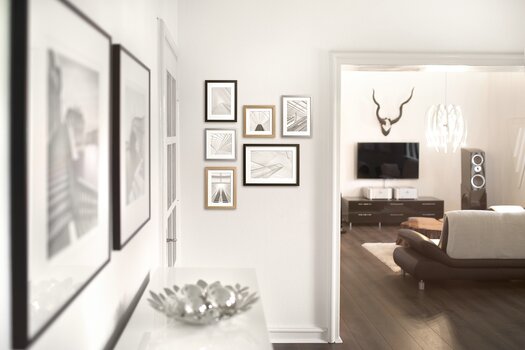 Gerahmte Bilder in verschiedenen Formaten und in verschiedenen Rahmen an Wohnzimmerwänden.