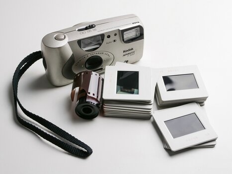 Kodak Kamera, davor ein Film und mehrere gerahmte Dias