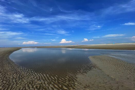 blauer Himmel mit wenigen Wolken, im Vordergrund Wasser und Sandboden blauer Himmel mit wenigen Wolken, im Vordergrund Wasser und Sandboden