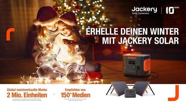 Junge Frau und Kind sitzen vor dem Weihnachtsbaum auf dem Boden und spielen mit einer leuchtenden Lichterkette. Diese wird mit dem daneben stehenden Jackery Explorer mit Strom versorgt. 