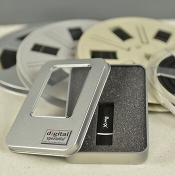 USB-Stick in Metalldose, im Hintergrund Filmspulen