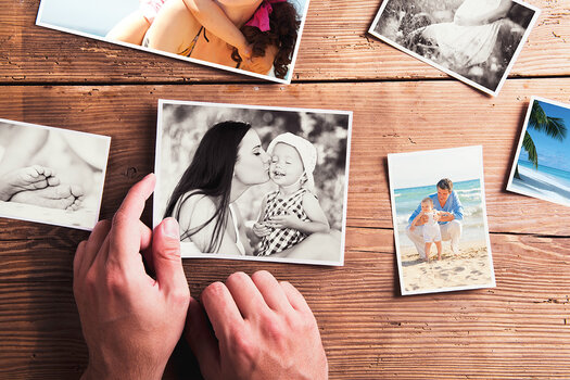 Betrachten und Auswählen mehrerer Familienfotos, die auf einem Holztisch liegen.