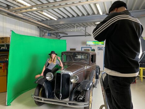 Studio Set-Up: Model lehnt an Oldtimer und wird vor dem Panorama Greenscreen fotografiert
