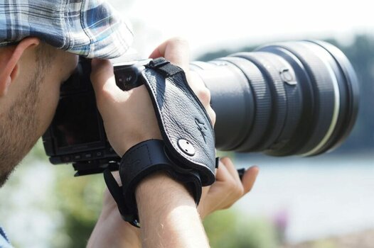 Mann fotografiert, Kamera ist mit einem Eddycam Sling am Handgelenk befestigt.