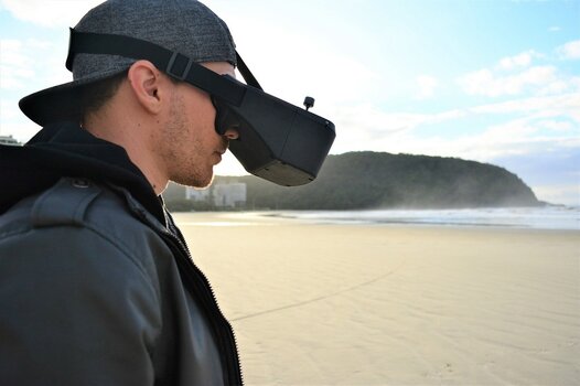 FPV-Drohnenpilot mit VR-Brille am Strand