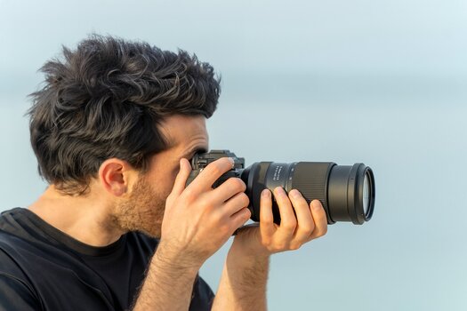 Mann fotografiert mit Tamron 70‑180mm F/2.8 Di III VC VXD G2 an Sony Kamera Mann fotografiert mit Tamron 70‑180mm F/2.8 Di III VC VXD G2 an Sony Kamera