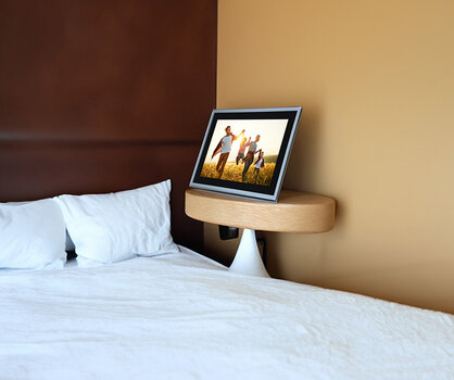 Smart Frame WiFi 102 Silver auf einer Holzkonsole neben einem Bett