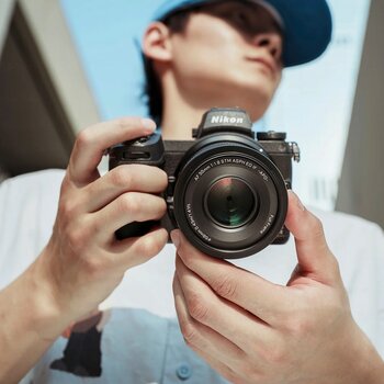 Eine Aufnahme aus der Perspektive eines Fotografen, der eine Nikon Z8-Kamera hält, die mit dem Viltrox AF 55mm F1.8 EVO-Objektiv ausgestattet ist. Die rechte Hand des Fotografen hält den Kameragriff, während die linke Hand das Objektiv abstützt. Die Kamera und das Objektiv sind direkt auf den Betrachter gerichtet. Am vorderen Filterring des Objektivs sind die Aufschriften „VILTROX“ und „AF 55mm 1:1.8 STM ASPH ED IF -APO-“ deutlich zu lesen.