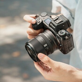 Nahaufnahme einer Person, die eine Nikon Z-Kamera mit dem montierten Viltrox AF 35mm F1.8 EVO Z hält. Der Fokus liegt auf der kompakten Bauweise des Objektivs und den seitlichen Bedienelementen wie dem AF/MF-Schalter und der runden Fn-Taste. Die Handhabung verdeutlicht die Handlichkeit des Objektivs für die Streetfotografie.