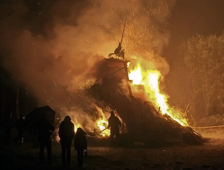 Menschen als Silhouetten vor einem großen lodernden Walpurgisfeuer bei Nacht