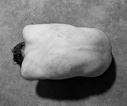 Schwarz-Weiß-Aufnahme eines skulptural zusammengerollten menschlichen Körpers aus der Vogelperspektive in einer minimalistischen Studioinszenierung. Schwarz-Weiß-Aufnahme eines skulptural zusammengerollten menschlichen Körpers aus der Vogelperspektive in einer minimalistischen Studioinszenierung.