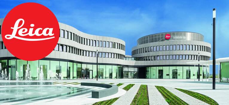 Die moderne Architektur des Leica Hauptsitzes im Leitz-Park Wetzlar mit einem großen, roten Leica Firmenlogo im Vordergrund.