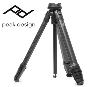 Das kompakte Peak Design Travel Tripod Carbon-Reisestativ in der Dreiviertelansicht mit dem Firmenlogo im Hintergrund.