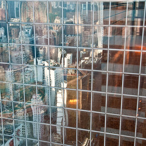 Skyline von Hong Kong verspiegelt vom gegenüberliegendem Gebäude, fotografiert durch eine Scheibe.