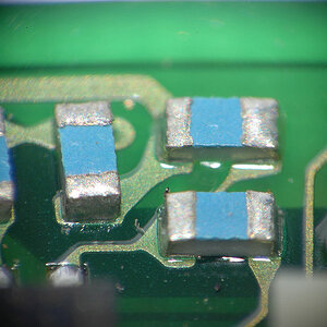 Mit selbstgebasteltem Lupenobjektiv (Maßstab 1:5,5):
Winzige SMD-Kondensatoren auf einer kleinen Nikon-AF-S-Motorplatine