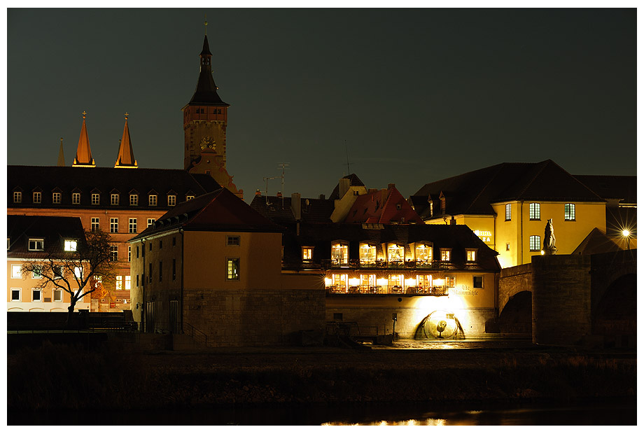 Das Bild zeigt die alte Mainmühle an der Würzburger Schleuse. Im Hintergrund erkennt man den Turm vom Rathaus.