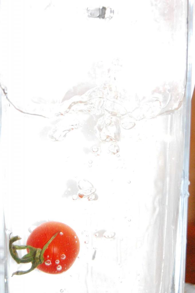 eine Tomate die ins Wasser fällt