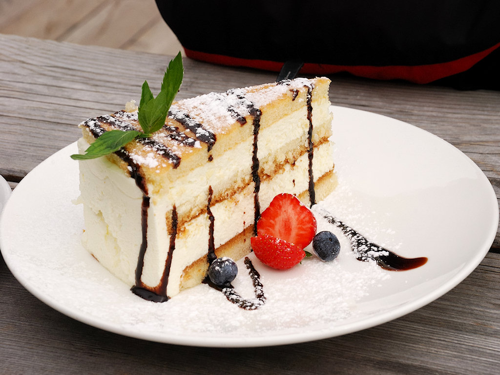 Käsekuchen mit Puderzucker, flüssiger Schokolade, Waldbeeren, Erdbeere und Pfefferminzblatt garniert.
Auf der Jimmy-Hütte am Grödner Joch.