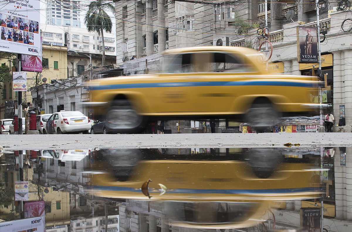 Nach einem Monsunregen spiegelt sich das Taxi in der Pfütze