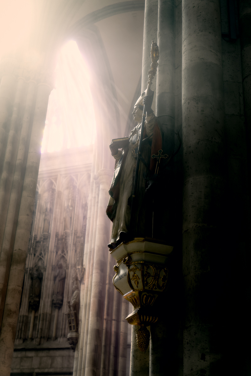 The sun is shining at a statue of a saint within the Cologne cathedral. 
The cathedral with its official name „High Cathedral of Saint Peter" is one o