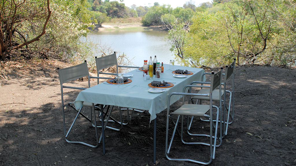 Tischlein-Deck-Dich
Das Mittagessen wurde in den Busch verlegt.
Am Lufupa River wurden mit dem Boot die Tische, Stühle, Kochutensilien und der Grill t