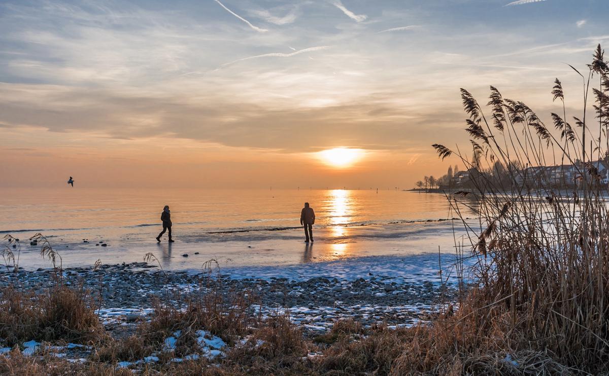 Winter am Bodensee

Spaziergänger genießen den Sonnenuntergang am gefrorenen Uferbereich