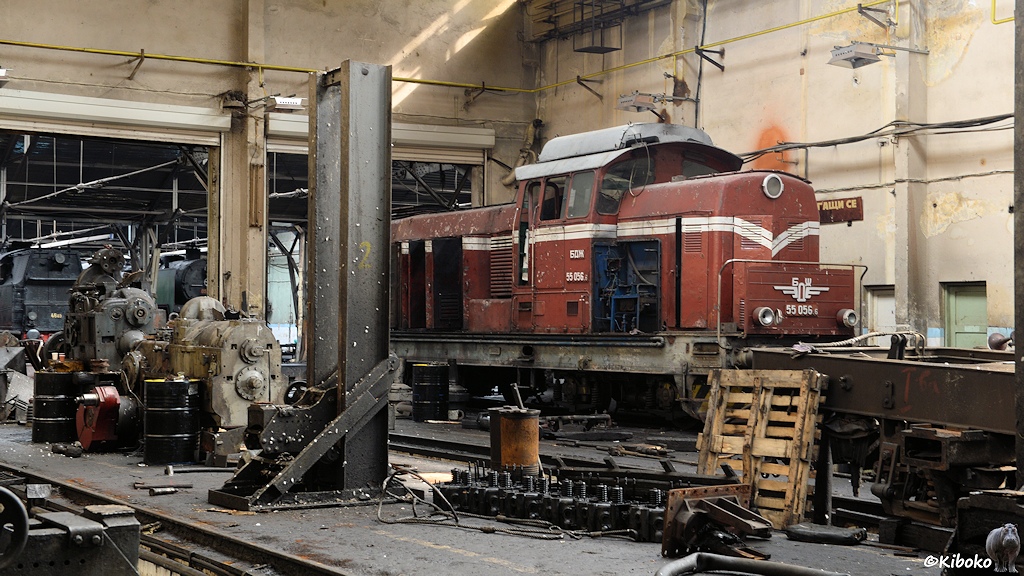 Das Bild zeigt eine rote Diesellok mit Mittelführerstand mit offenen klappen zwischen Motoren und Getrieben in einer Werkhalle.