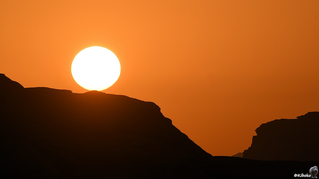 Die Sonnenscheibe berührt die Bergkette