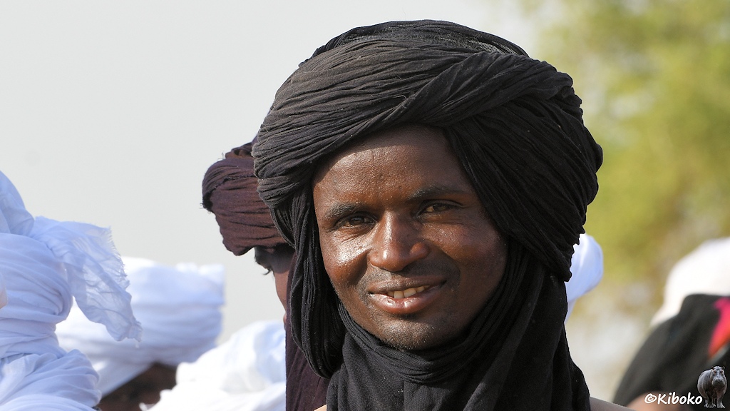 Das Bild zeigt das Proträt eines lächelndes Mannes mit schwarzem Turban.