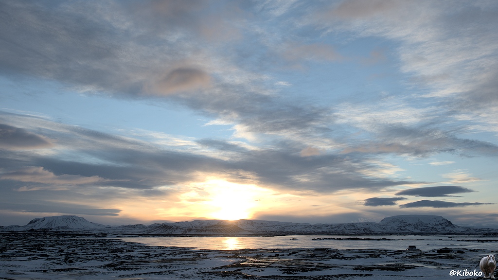 Landschaftsaufnahme eines zugefrorenen Sees bei Sonnenaufgang.