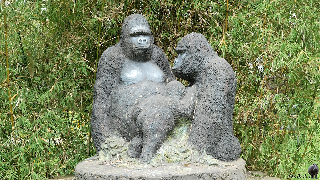 Das Bild zeigt eine Statue mit zwei erwachsenen Gorillas und einen Junggorilla for einem Bambusgestrüpp.