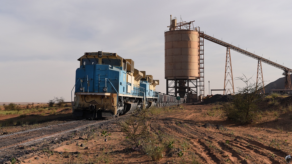 Die Loks stehen mit den ersten beladenen Erzwagen vor dem gelben Verladesilo.