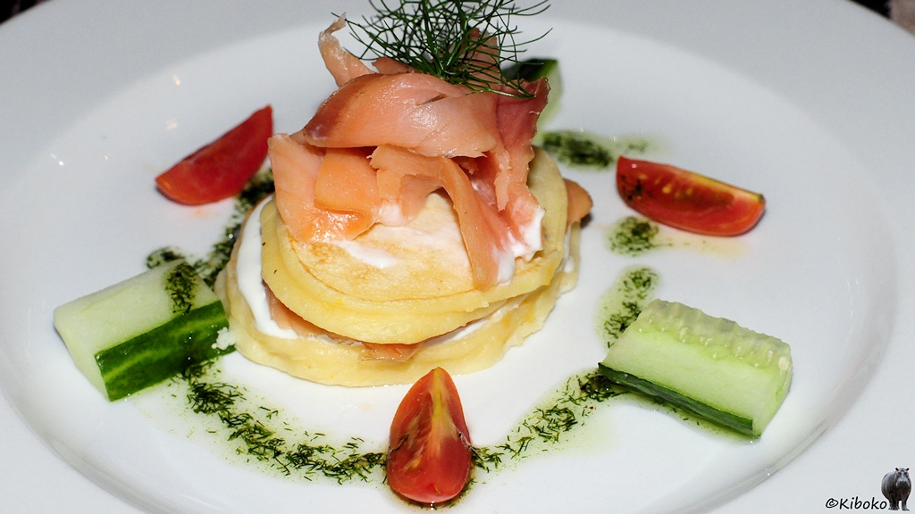 Die Vorspeise mit Lachsstreifen ist mit Dill, Tomaten und Gurken dekoriert.