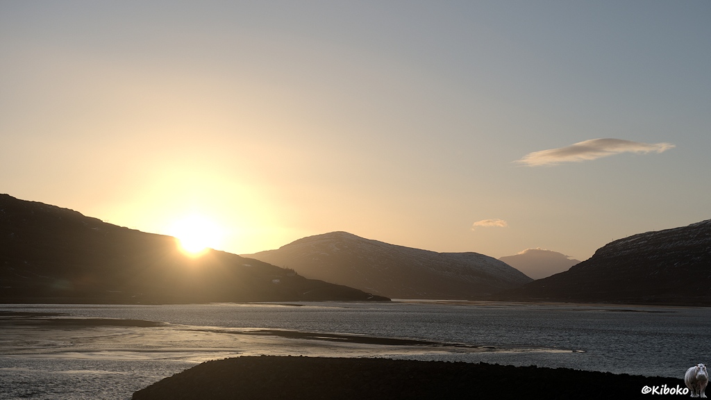 Sonnenuntergang über einen See mit einer Bergkette im Hintergrund.