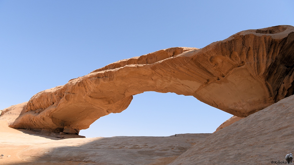 Flacher Steinbogen aus beigen Sandstein gegen den blauen Himmel fotografiert