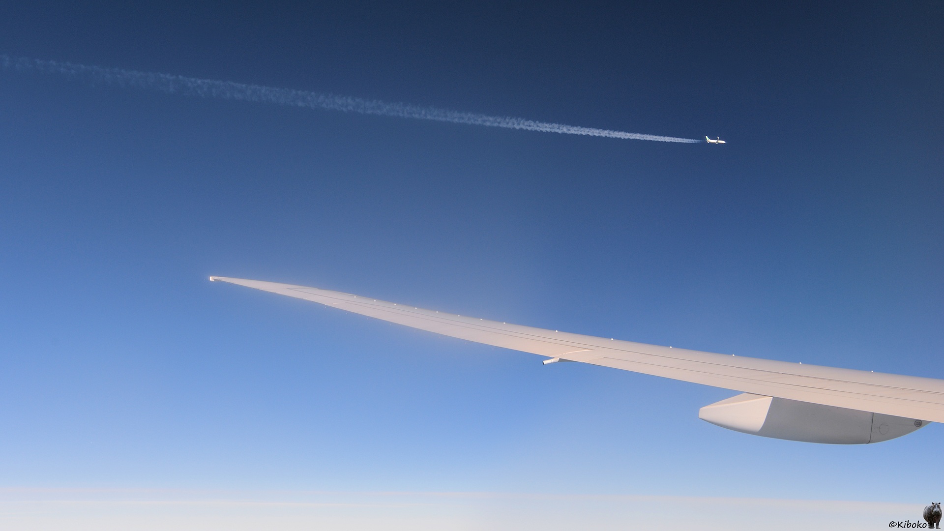 Blick auf dem Flugzeugenster. Über der Trafgfläche ist ein Flugzeug.