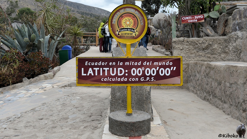 Das Bild zeigt einen betonierte Fläche mit einer roten Linie, die nur am unteren Bildrand sichtbar ist. Darauf steht ein braunes Schild mit der Aufschrift: Latitud: 00°00 00, calculada con G.P.S.