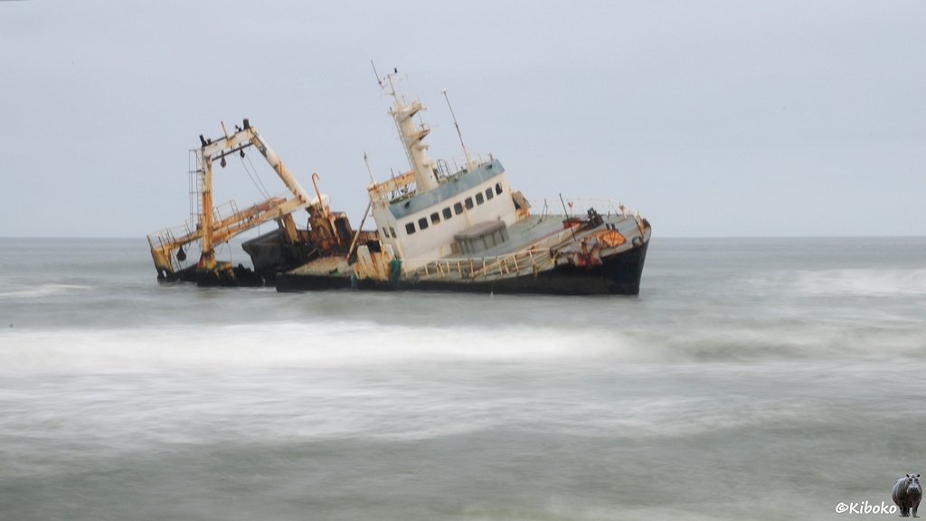 Ein Fischtrawler in Schräglage mit dunkelblauem Rumpf und weißen Aufbauten in umtosten Wellen.