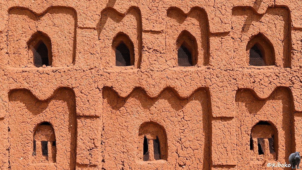 Das Bild zeigt einen Ausschnitt der Moschee. Unten sind zwei Fenster mit Säulenstützen. Oben sind vier kleine Fenster. Die Fenstger sind jeweils etwas zurückversetzt und mit Kaninchendraht bespannt.