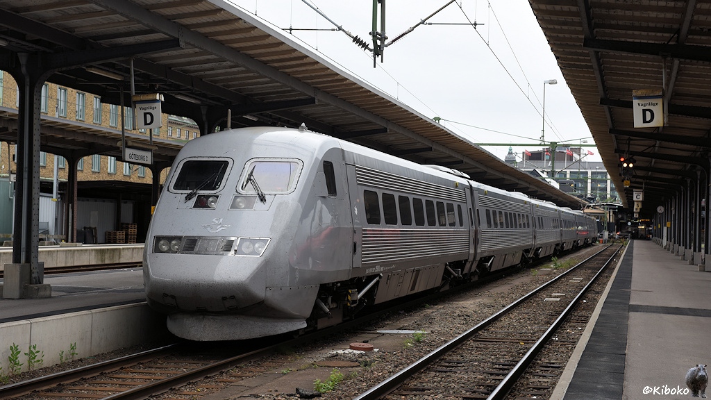 Das Bild zeigt einen siebenteiligen, grauen Schnelltriebwagen mit dem Steuerwagen voraus am Bahnsteig stehen. Die Seitenwände haben silberne Sickenprofile.