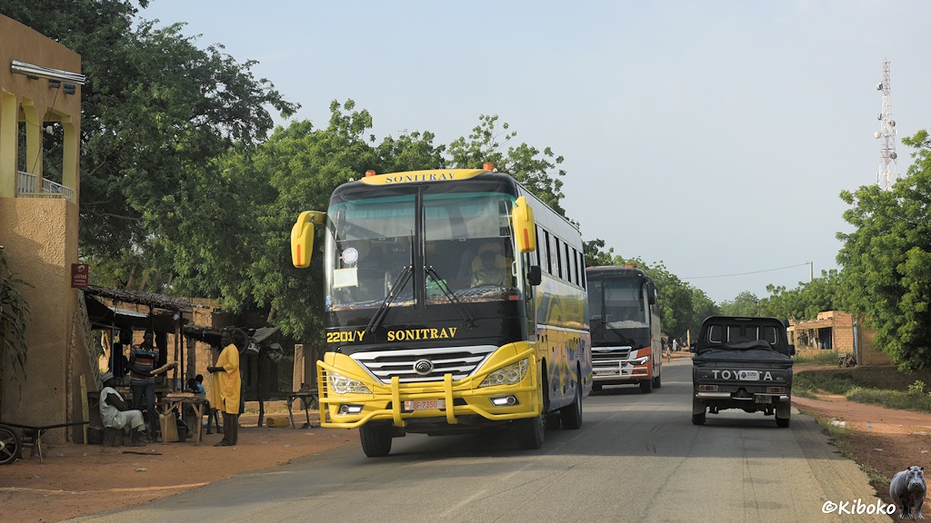 Das Bild zeigt zwei entgegenkommende Reisebusse und einen vorausfahrenden Geländewagen auf einer Teerstraße. Der erste Reisebus ist Gelbschwarz und gehört der Unternehmen Sonitrav.