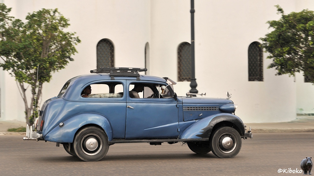 Das Bild zeigt ein sehr altes amerikanisches Auto von der Seite. Das Auto ist dunkelblaumetallic lackiert und hat große Radkästen. Die Scheinwerfer sind außen an der langen Motorhaube montiert. Die Kühlervigur ist ein silberner Schwan. Auf der Haube ist eine große silberne Zweiklangfanfare. Auf der Heckstoßstange ist eine Funkantenne.