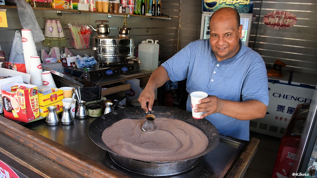 In einer großen Runden Pfanne mit heßem braunen Sand wird der Kaffee in einem kleinen Kännchen gekocht