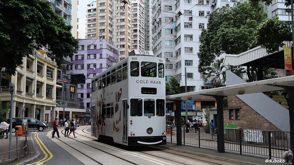 Das Bild zeigt eine weiße Tram mit der Nummer 154 an einer Haltestelle. Im Hintergrund sind Hochhäuser. Ein Hochhaus ist lila angemalt.