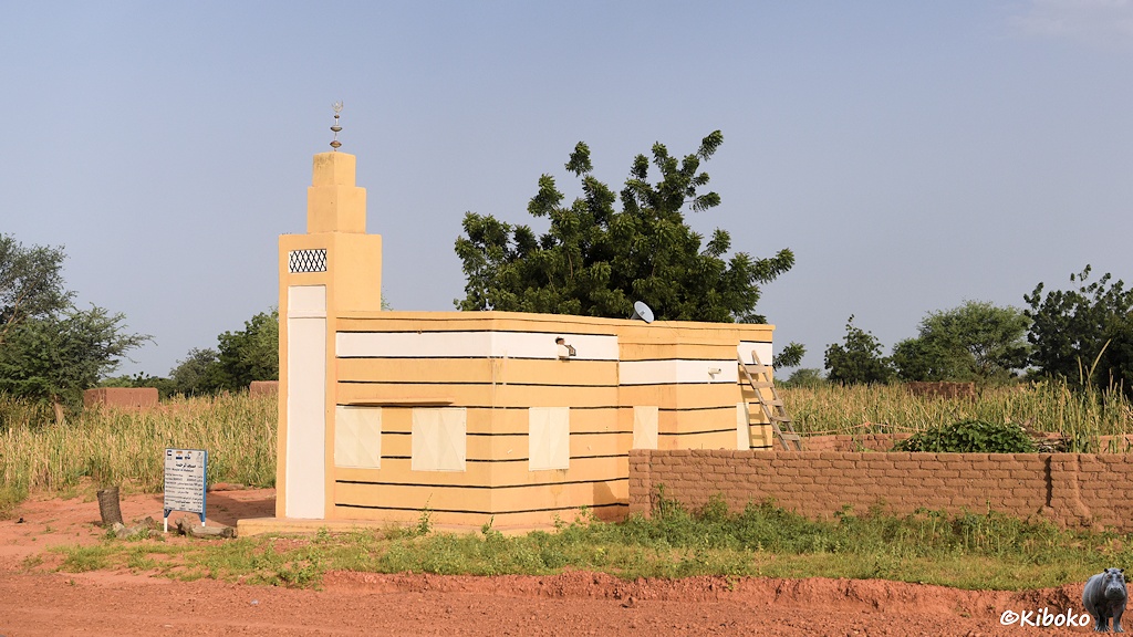 Das Bild zeigt eine kleine beige Moschee mit den Abmessungen einer Garage. An der linken Ecke ist ein kleiner eckiger Turm, der die Moschee nur knapp überragt.