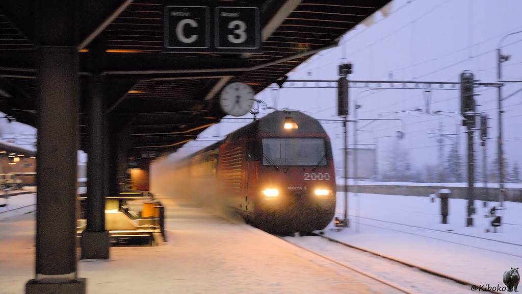 Das Bild zeigt einen Personenzug bei der schnellen Vorbeifahrt am Bahnsteig in der Dämmerung. Das Bild ist ein Mitzieher. Nur die Loknummer ist halbwegs scharf.
