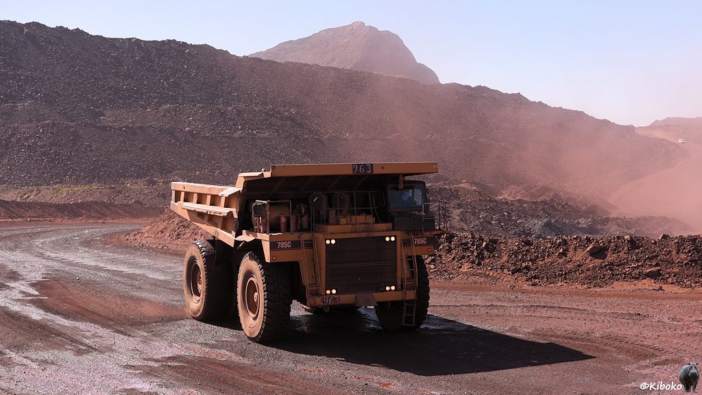 Leerer Kipper-LKW fährt durch rote, verstaubte Landschaft zurück in die Mine.