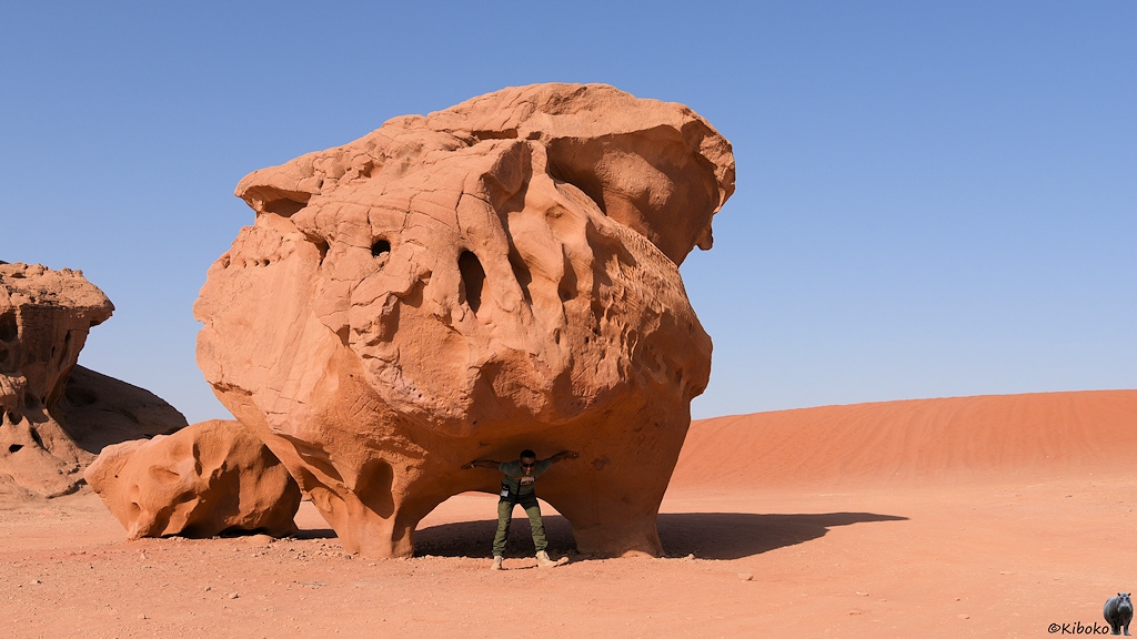 Pilzförmige Steinskulptur wird von einen Menschen gestützt